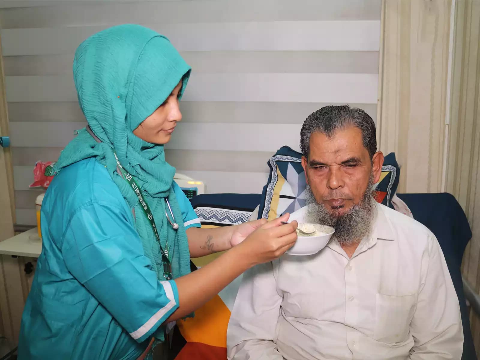 Nursing Care at home — a registered nurse checking on a patient resting in a hospital bed